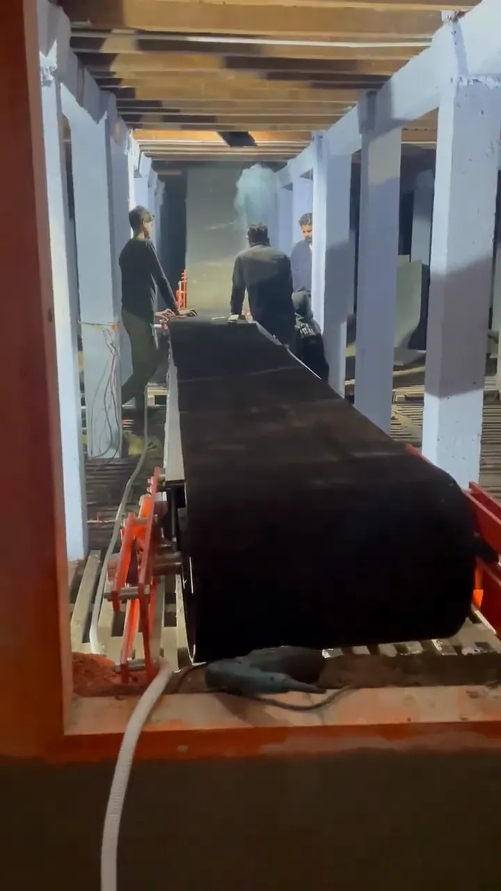 Conveyor belt running inside a cold store while workers guide the load