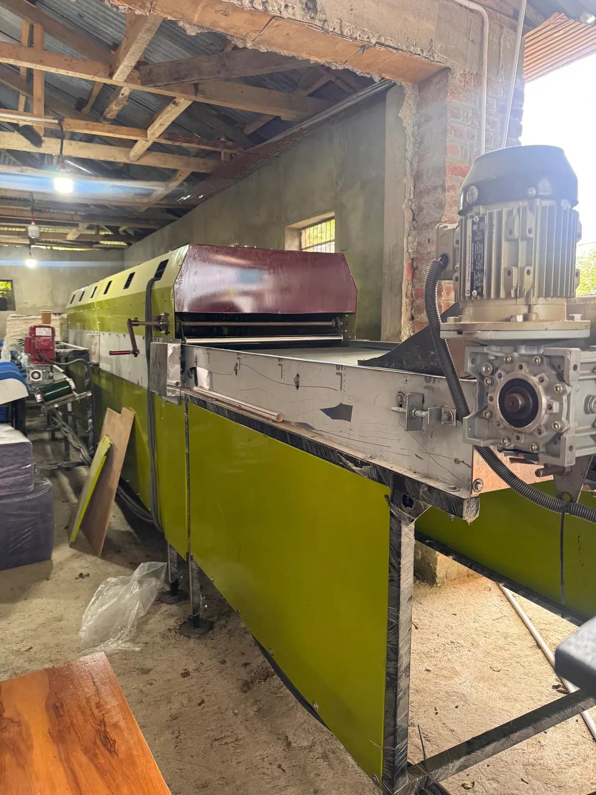 Flat belt conveyor with a geared motor on a green frame